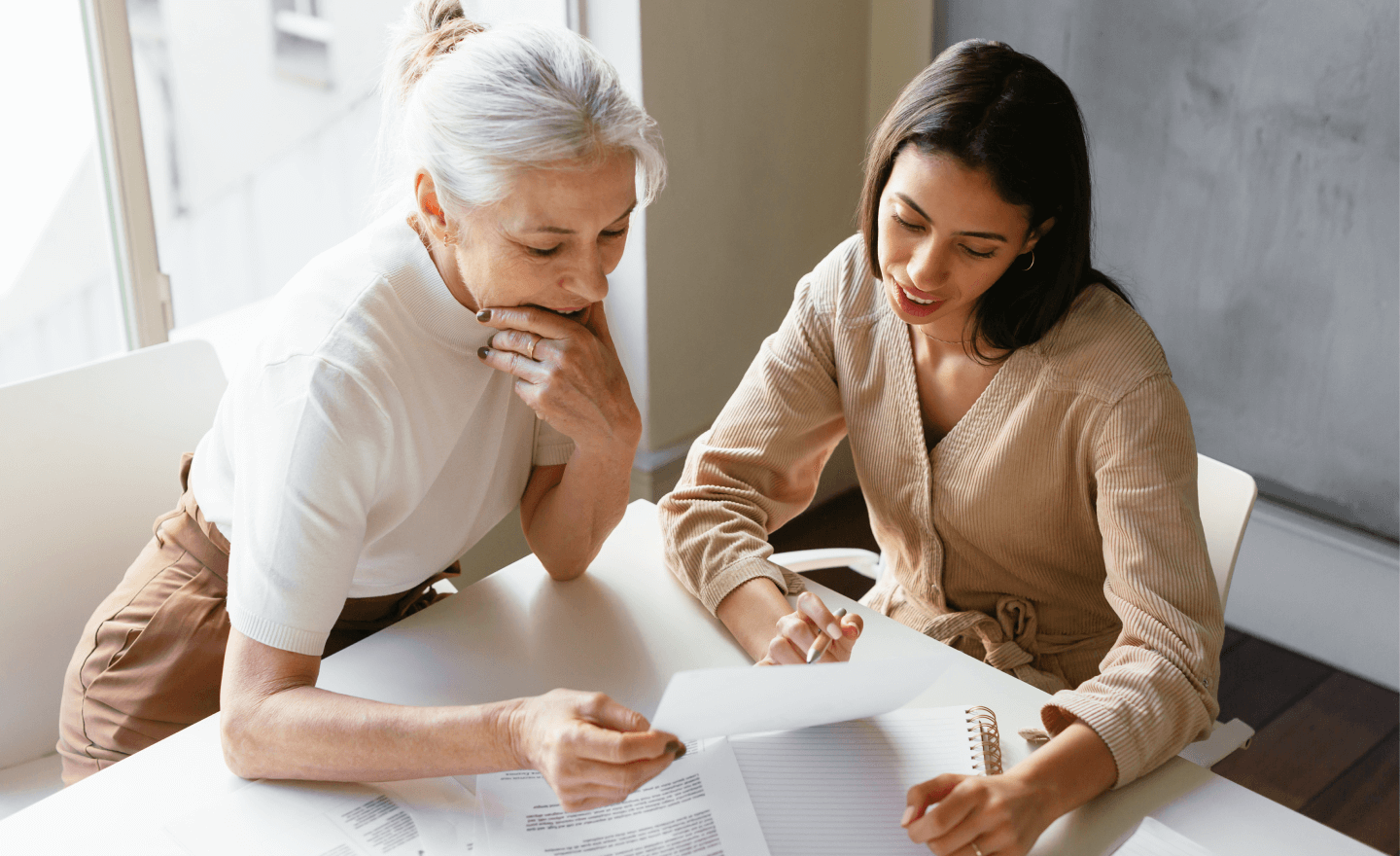 Image of two women contemplating their work at a table