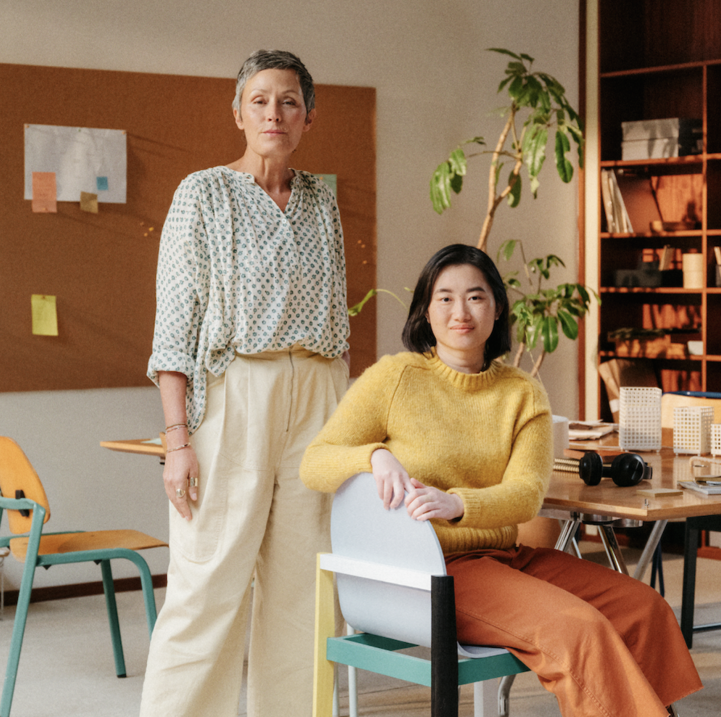 Two women posing in a warm toned office